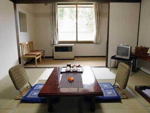a living room with a wooden table and chairs at Yunosawa Onsen Mori no Shiki in Shimukappu