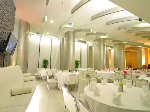 uma sala de jantar com mesas brancas e cadeiras brancas em Mayflower Grande Hotel em Hat Yai