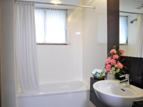 un bagno bianco con lavandino e vasca di Mayflower Grande Hotel a Hat Yai