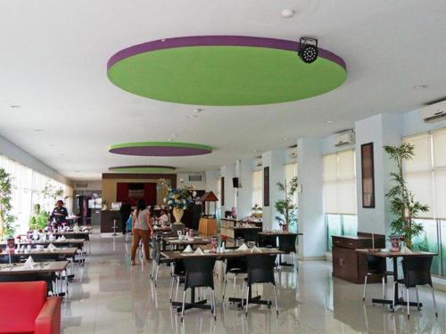 restauracja ze stołami i krzesłami oraz zielonym sufitem w obiekcie Le Man Hotel Lampung w mieście Umbulan Tulungmeris