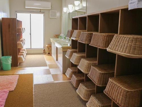 a room with shelves with wicker baskets and a sink at Hotel New Otsuka in Shirako