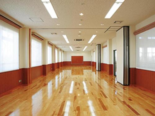 a large room with a wooden floor and windows at Hotel New Otsuka in Shirako