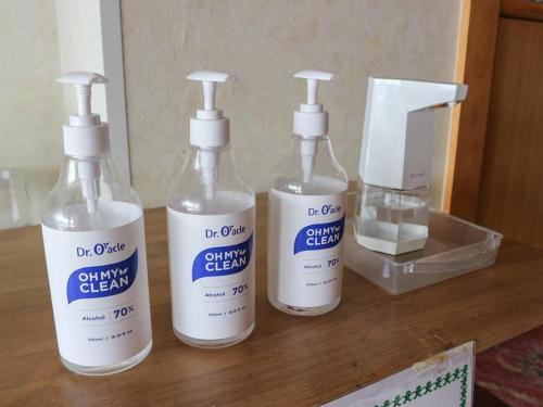three bottles of cleaning products sitting on a wooden counter at Hotel New Otsuka in Shirako