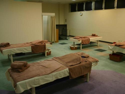 a room with three beds in a room at Hokkaido Futomi Meisen Manyo no Yu in Ishikari