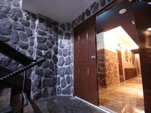 a room with a stone wall and a wooden door at Gallery Hotel in Daegu
