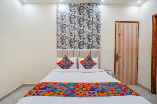 een slaapkamer met een bed met een kleurrijke deken bij FabHotel ADA Residency in Noida