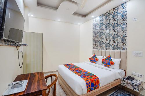 een slaapkamer met een bed en een tafel en een televisie bij FabHotel ADA Residency in Noida
