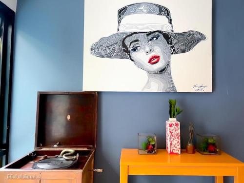 a painting of a woman wearing a hat on a wall at BB House Mini Suite Hotel in Ban Zong Katiam