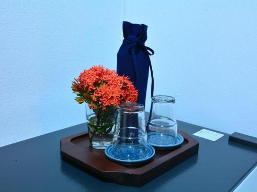 a tray with a vase of flowers and glasses on a table at The Indigo House Phrae in Phrae