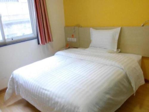 duże białe łóżko w pokoju z oknem w obiekcie 7 Days Inn Yan'an Baotashan w Yan'an
