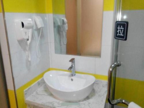 7 Days Inn Yan'an Baotashan في يانان: حمام مع حوض ومرآة وهاتف
