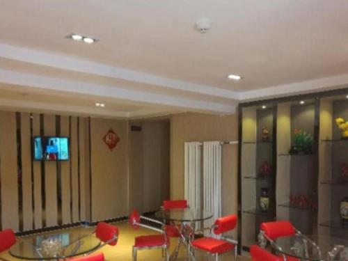 um quarto com uma mesa de vidro e cadeiras vermelhas em 7 Days Premium Hohhot Hailiang Square em Hohhot