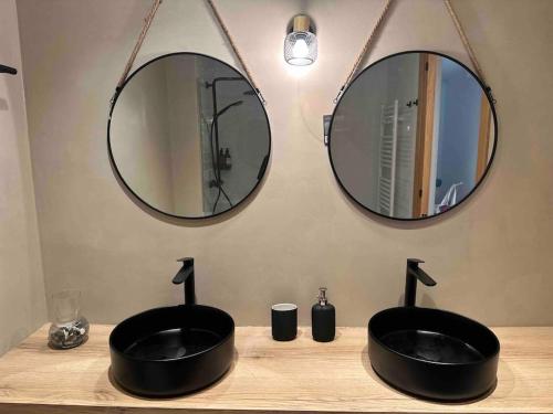 a bathroom with two sinks and two mirrors at Cal Manubens in Castellar del Riu