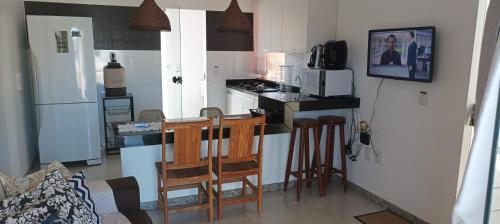 een keuken met een koelkast en een aanrecht met stoelen bij Porto Ville Home - AP 2 quartos in Porto Seguro