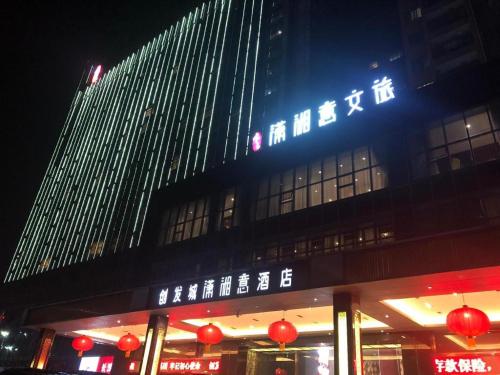 a building with a sign on top of it at night at Yongzhou Chuang Fa Cheng XiaoXiangYi Hotel in Guzhuting