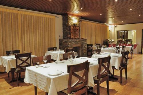 a restaurant with white tables and chairs and a fireplace at Khang Residency Thimphu in Thimphu