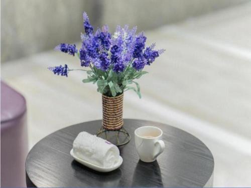 a table with a vase of purple flowers and a cup of coffee at Lavande Hotel Yichang Railway East Station Branch in Baiyang