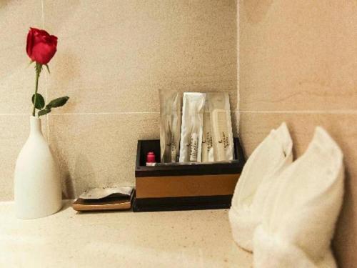 czerwona róża w białej wazie obok pudełka w obiekcie Lavande Hotel Yichang Railway East Station Branch w mieście Baiyang
