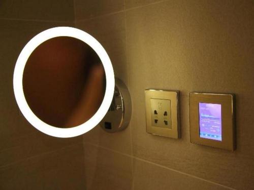 a mirror on a wall next to a lightswitch at Lavande Hotel Yichang Railway East Station Branch in Baiyang