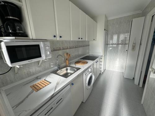 a white kitchen with a sink and a microwave at Apartamento Muchavista Primera Línea de Playa By El Conserje in El Campello