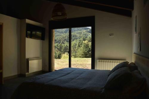 a bedroom with a blue bed and a large window at Cal Manubens in Castellar del Riu