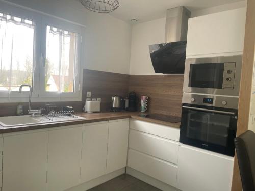 une cuisine avec des armoires blanches et un micro-ondes dans l'établissement Pavillon à 10 min Disney/Paris/Val d'Europe, à Montévrain