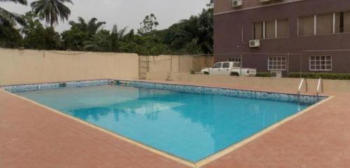 a large blue swimming pool in front of a building at GADE PLACE HOTEL in Alakohia