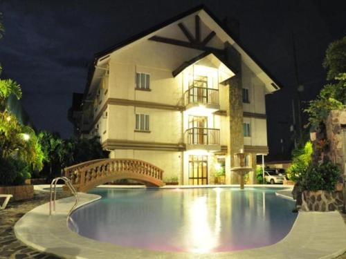 a swimming pool in front of a building at night at Chocolate and Berries Hotel in Baliuag