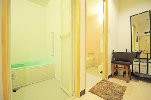 ein Badezimmer mit einer Badewanne, einem Stuhl und einem Spiegel in der Unterkunft B&B Yado Kitakai in Kikonai