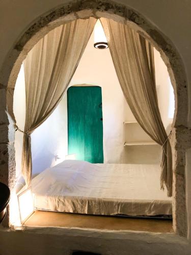 a bedroom with a bed with a green door at Dar Kenza in Djerba