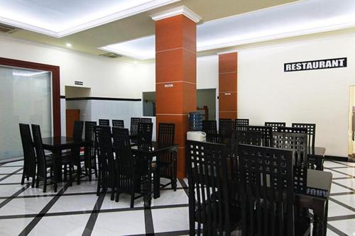 een restaurant met zwarte tafels en stoelen in een kamer bij Hotel Banggalawa in Jakarta