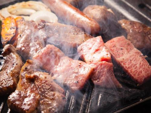 a bunch of meat and other foods cooking on a grill at Yufuin Tsukahara Villa ERINA in Yufuin