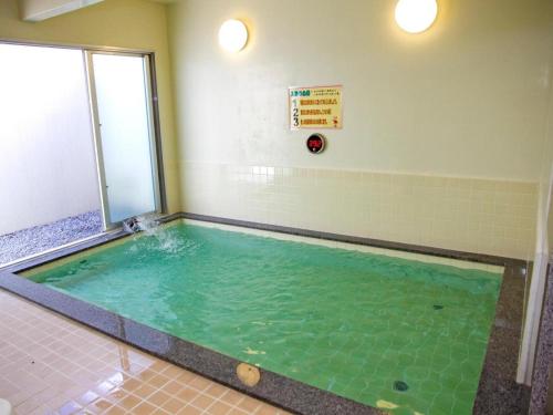 a swimming pool with green water in a room at Nature Miraikan in Naha