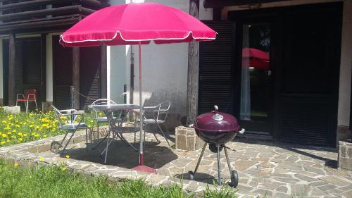 a grill and a pink umbrella on a patio at Apartma Rogla Gaber 110 in Zreče