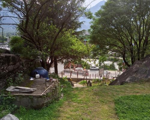 a yard with a tent and a fence and trees at Mashoo Resorts , Bhuntar in Shamshi