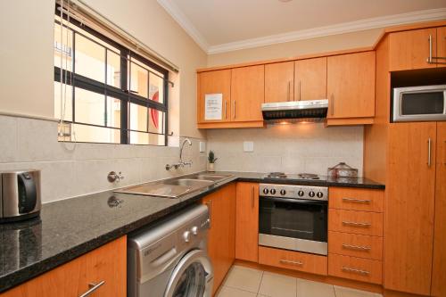 a kitchen with wooden cabinets and a washer at Vilaroux in Stellenbosch