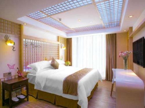 a bedroom with a large white bed and a television at Vienna Hotel - Shenzhen Dongmen Hubei Metro Station in Shenzhen