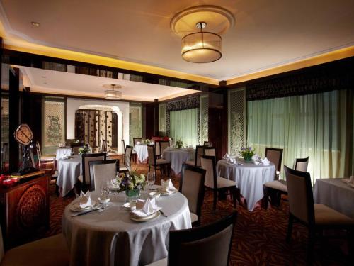 a dining room with white tables and chairs at Tongxiang Inspirock Hotel in Jiaxing