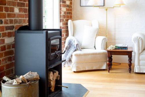 a living room with a wood stove with a chair at Harland Rise Chapel Circa 1830 in Evandale