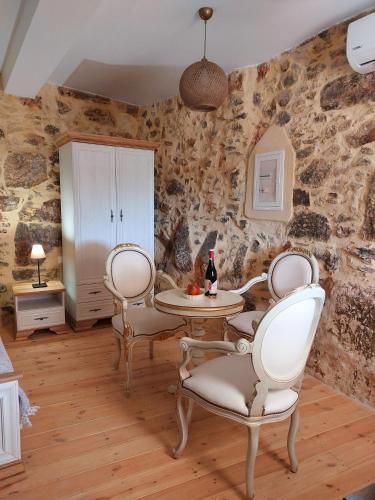 a dining room with stone walls and a table and chairs at Roza Stone Studio & Suite in Goníai