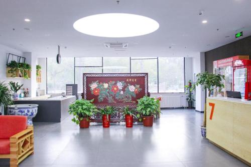 7 Days Premium Beijing Dabaotai Metro Station Luhua Road في بكين: غرفة بها نباتات الفخار ولوحة على الحائط