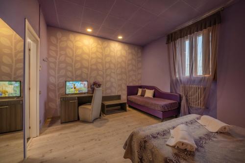 a bedroom with a bed and a couch and a tv at Hotel Palazzo Renieri - 3stelle S in Colle Val D'Elsa
