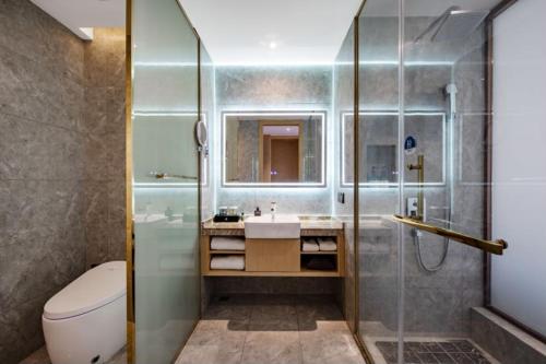 a bathroom with a shower and a toilet and a sink at Huaian Reykana Hotel in Huai'an