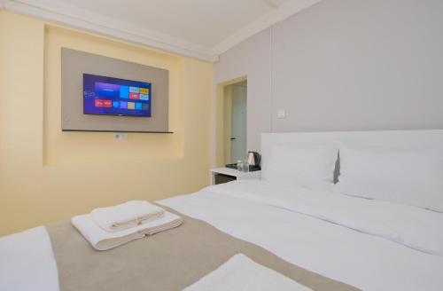 a bedroom with a white bed with a tv on the wall at Lucky Hotel İstanbul in Istanbul