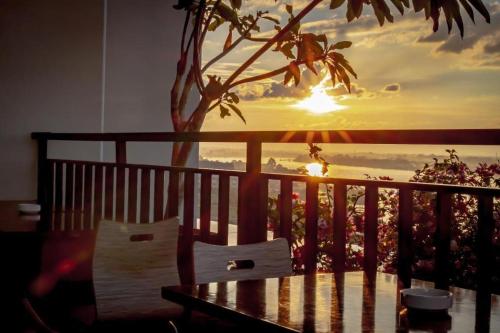 a table and chairs on a balcony with a sunset at Infinity Hotel Jambi by Tritama Hospitality in Jambi
