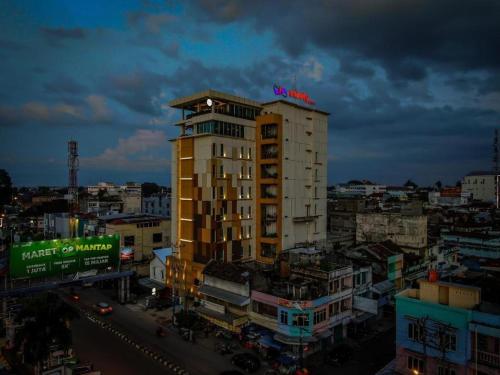 Infinity Hotel Jambi by Tritama Hospitality في جامبي: مبنى طويل عليه لافتة نيون