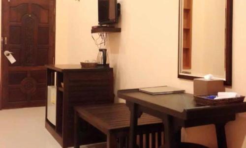 een kamer met een houten bureau, een tafel en een deur bij Pharadhevi in Ban Dung