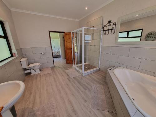 a bathroom with a tub and a toilet and a sink at Milkwood Cottage in Bettyʼs Bay