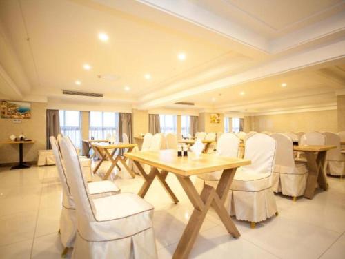 uma sala de jantar com cadeiras brancas e uma mesa de madeira em GreenTree Inn Yancheng Tinghu Area Wengang Road New Fourth Army Memorial Hotel em Yancheng