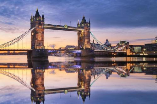 un puente colgante sobre un río con su reflejo en el agua en Travelodge London Central City Road en Londres